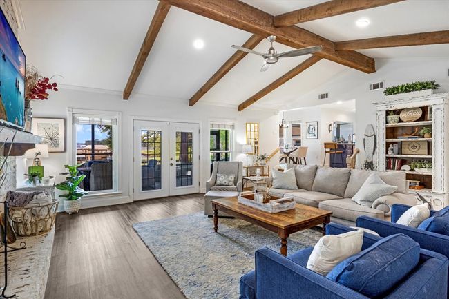Living area with wood finished floors, visible vents, a ceiling fan, and vaulted ceiling with beams | Image 5