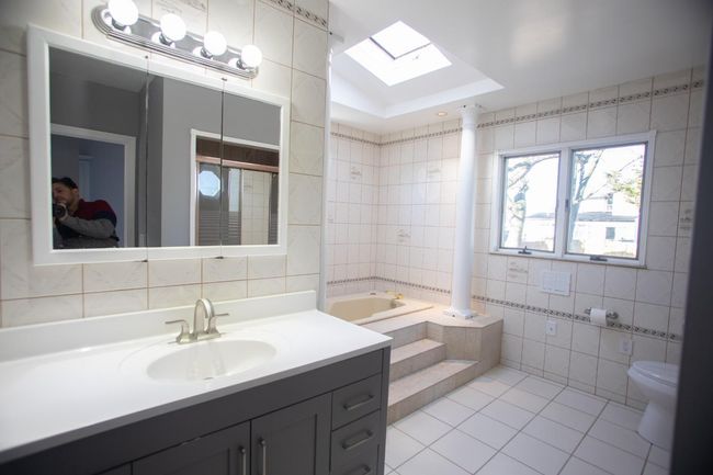 Bathroom featuring tile patterned floors, tile walls, tiled bath, and a skylight | Image 14