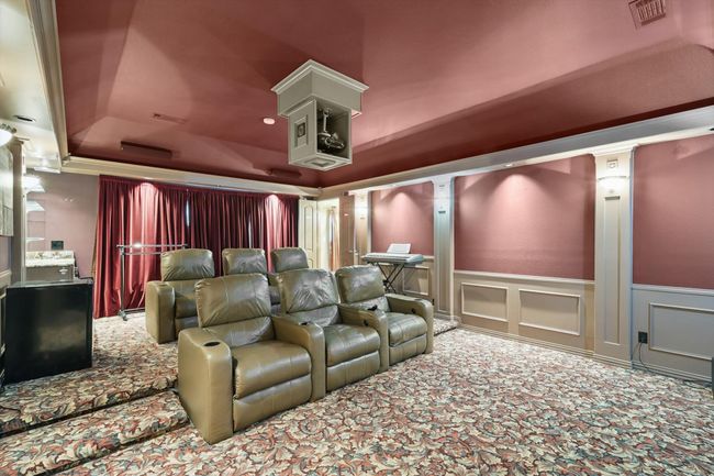 Carpeted home theater featuring a raised ceiling, a wainscoted wall, and a decorative wall | Image 20
