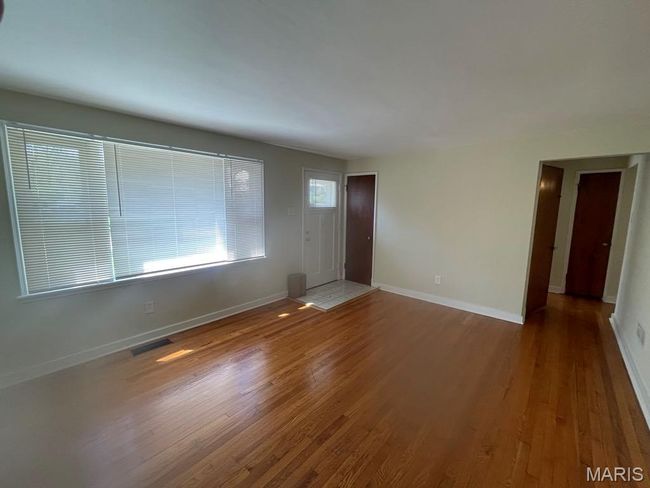 Unfurnished living room featuring baseboards, wood finished floors, and visible vents | Image 4