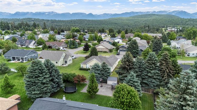 Aerial view of residential area with a mountainous background and a heavily wooded area | Image 12