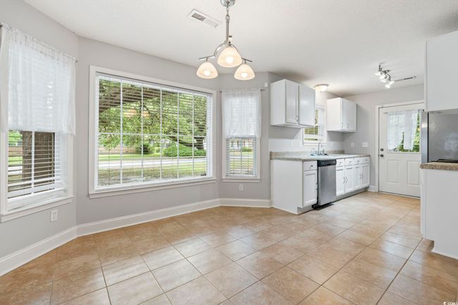 Kitchen featuring appliances with stainless steel finishes, light tile patterned flooring, white cabinets, and light countertops | Image 9