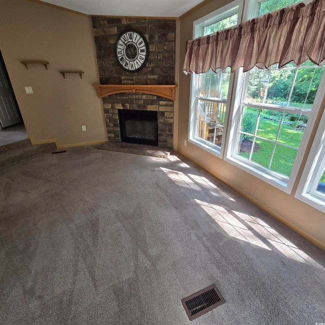 Unfurnished living room featuring carpet floors and a stone fireplace | Image 21