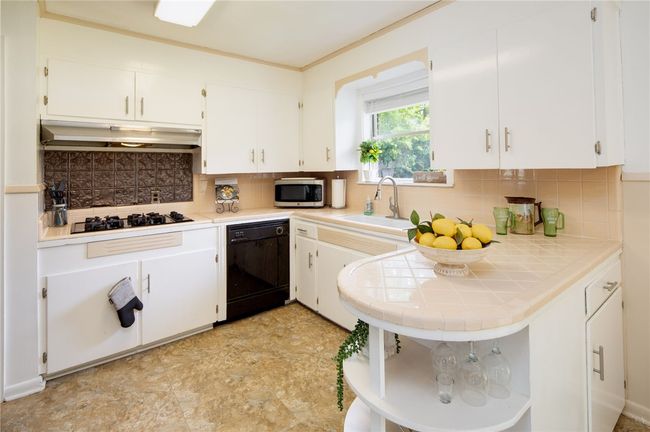 Kitchen featuring black appliances, open shelves, white cabinets, tile countertops, and crown molding | Image 8