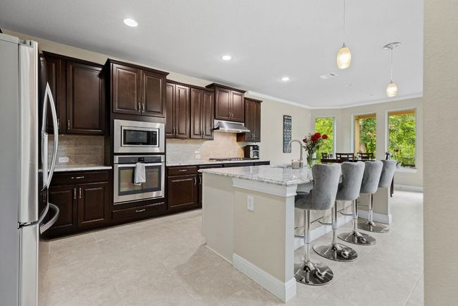 Kitchen with stainless steel appliances, under cabinet range hood, backsplash, recessed lighting, and a kitchen bar | Image 8