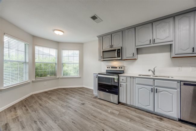 Kitchen with appliances with stainless steel finishes, light wood-style floors, gray cabinetry, and tasteful backsplash | Image 5