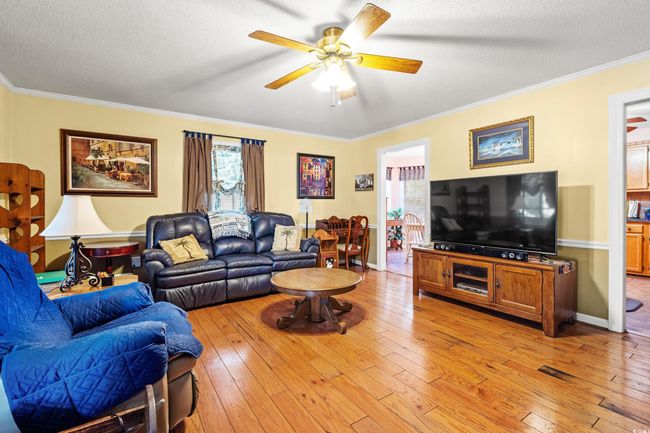 Living area featuring plenty of natural light, a ceiling fan, ornamental molding, a textured ceiling, and light wood-style floors | Image 9