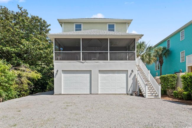 View of front facade featuring a sunroom, stairway, an attached garage, gravel driveway, and roof with shingles | Image 39