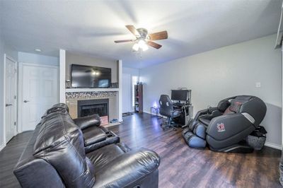 Living room featuring a textured ceiling, dark hardwood / wood-style flooring, ceiling fan, and a large fireplace | Image 3