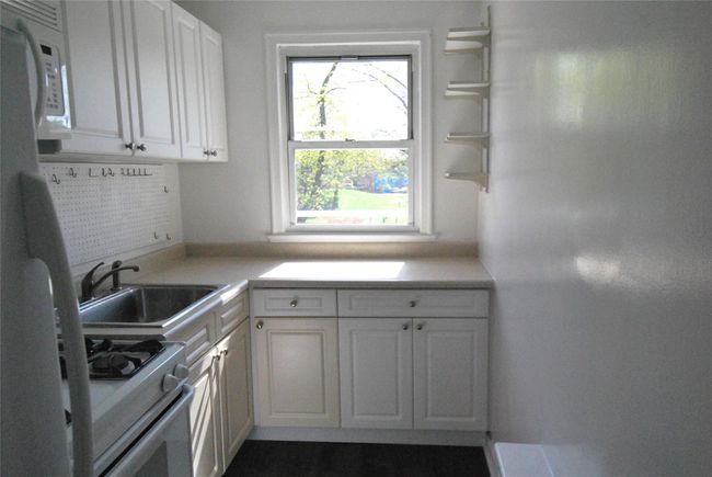 Kitchen featuring light countertops, white cabinetry, a sink, and white appliances | Image 8