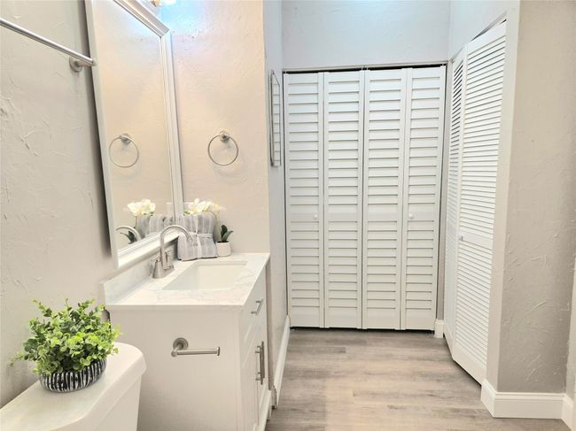 Bathroom with a closet, vanity, wood finished floors, and a textured wall | Image 14