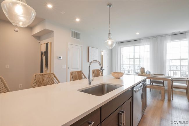Kitchen with a sink, dishwasher, pendant lighting, light countertops, and visible vents | Image 11