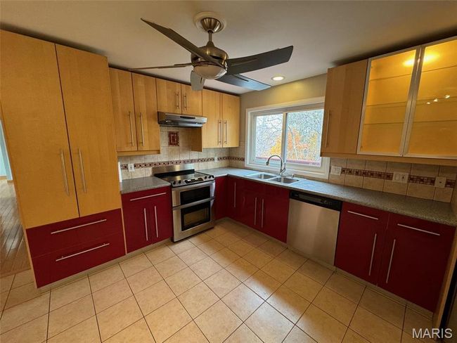 Kitchen with decorative backsplash, appliances with stainless steel finishes, sink, and ceiling fan | Image 4