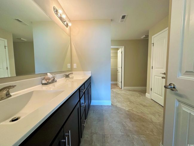 Bathroom featuring baseboards, double vanity, a sink, and visible vents | Image 8