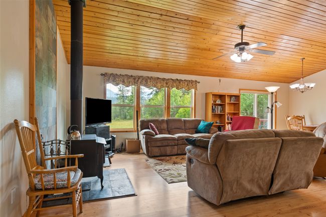 Living room with a wood stove, wood ceiling, lofted ceiling, a ceiling fan, and a chandelier | Image 20