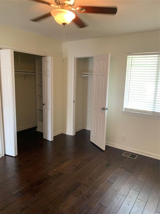 Unfurnished bedroom featuring dark wood-style flooring, multiple closets, baseboards, and a ceiling fan | Image 14