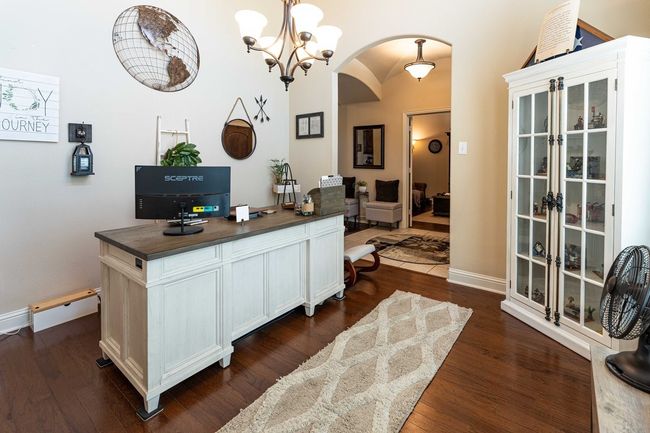 Dining with arched walkways, dark wood-style flooring. Currently used as a home office | Image 7