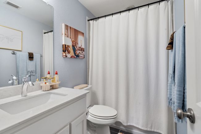 Bathroom featuring vanity, a textured wall, curtained shower, and tile patterned floors | Image 21