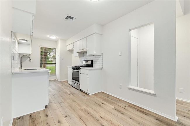 Kitchen with stainless steel range with gas cooktop, light wood-style floors, under cabinet range hood, and a sink | Image 6