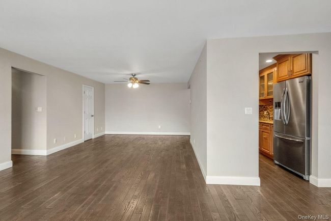 Unfurnished living room with dark wood-type flooring, baseboards, and a ceiling fan | Image 8