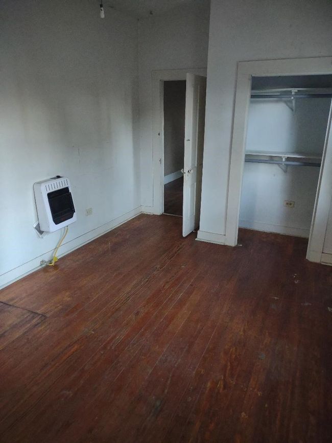 Unfurnished bedroom with baseboards, a closet, hardwood / wood-style flooring, and heating unit | Image 20