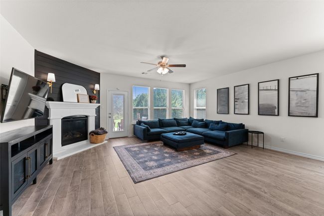 Living room featuring a glass covered fireplace, wood finished floors, and a ceiling fan | Image 11