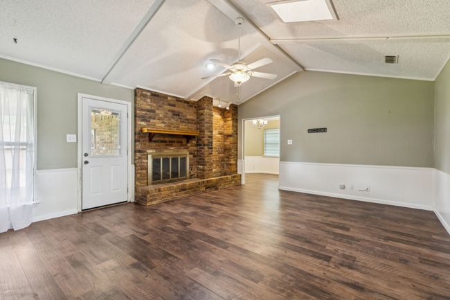 Unfurnished living room featuring a textured ceiling, a skylight, healthy amount of natural light, ceiling fan, and a fireplace | Image 7