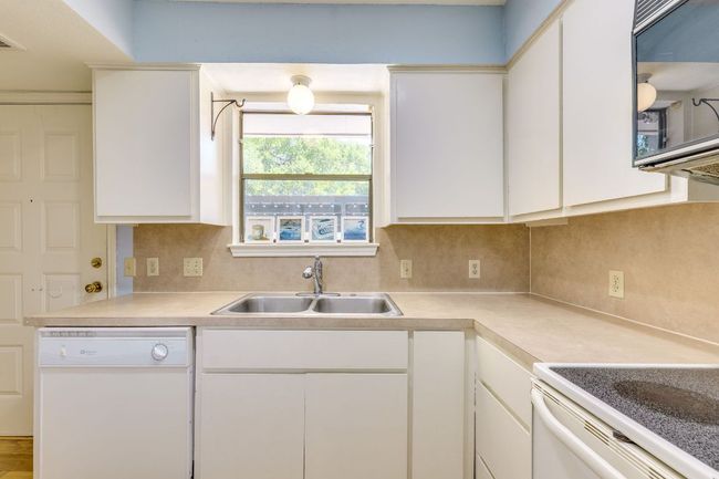 Kitchen featuring white appliances, a sink, decorative backsplash, and light countertops | Image 8