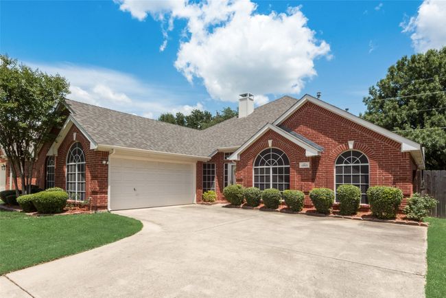 View of front of home with brick siding, roof with shingles, concrete driveway, an attached garage, and a chimney | Image 6