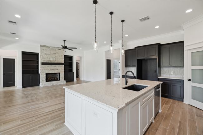 Kitchen featuring pendant lighting, sink, a fireplace, an island with sink, and stainless steel dishwasher | Image 18