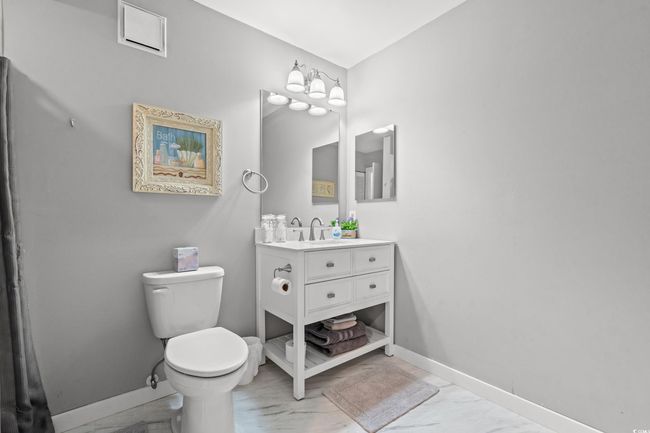 Bathroom with marble look tile flooring, vanity, toilet, and baseboards | Image 20