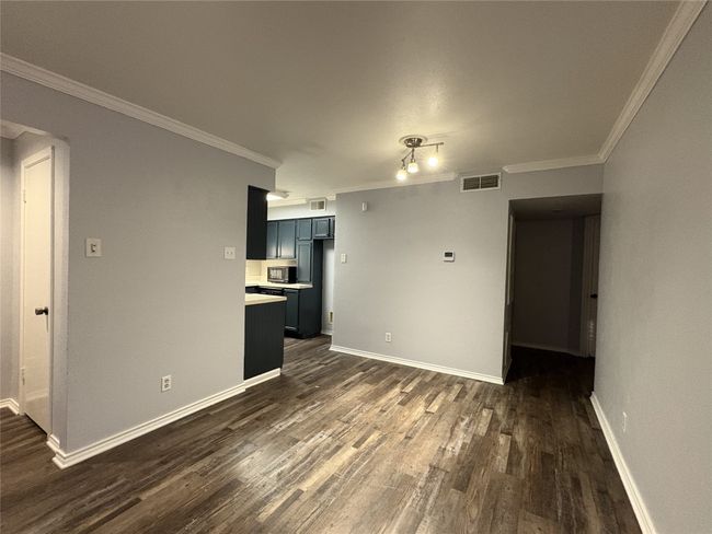 Unfurnished living room with dark wood-style floors and crown molding | Image 7