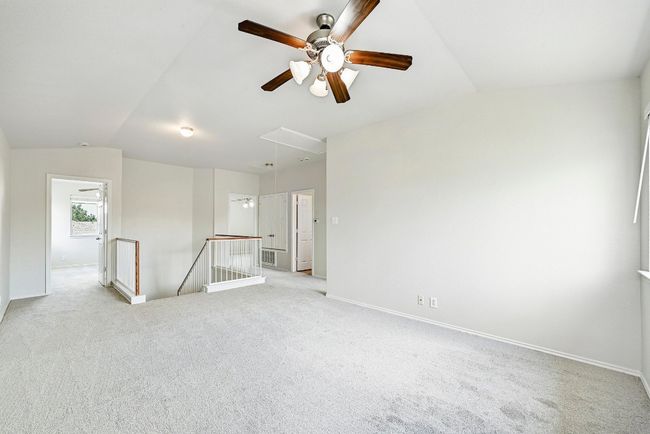 Empty room with attic access, vaulted ceiling, light colored carpet, and a ceiling fan | Image 13