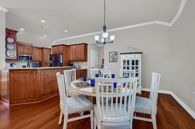 Dining room with lofted ceiling, crown molding, wood finished floors, and an inviting chandelier | Image 11
