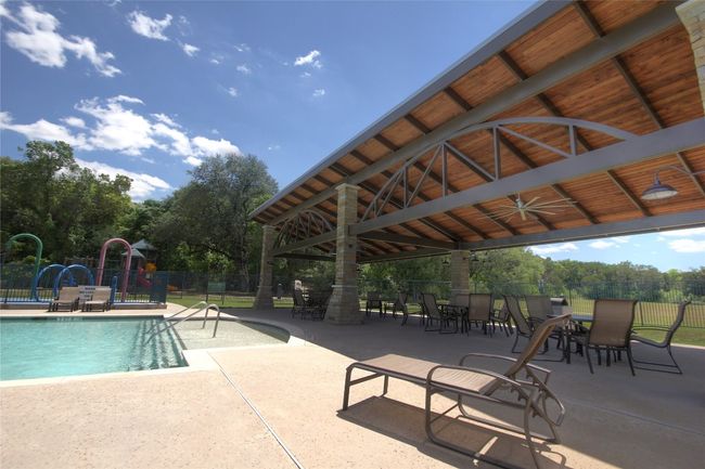 Community pool with a gazebo, ceiling fan, a patio area, and view of wooded area | Image 25
