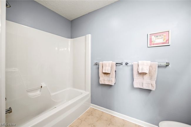 Bathroom with tile floors, tub / shower combination, and a textured ceiling | Image 27