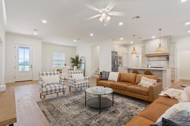 Living room with light wood finished floors, recessed lighting, a ceiling fan, and stairs | Image 7