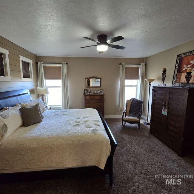 Bedroom with multiple windows, dark colored carpet, a textured ceiling, and ceiling fan | Image 16