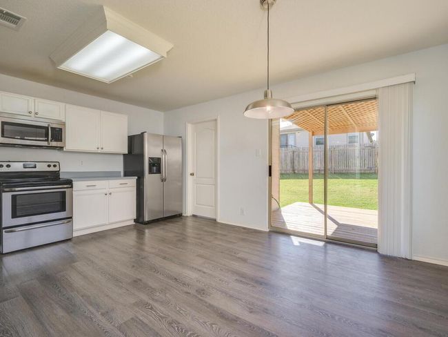 Kitchen featuring appliances with stainless steel finishes, luxury vinyl wood-look flooring, and white cabinetry. | Image 9