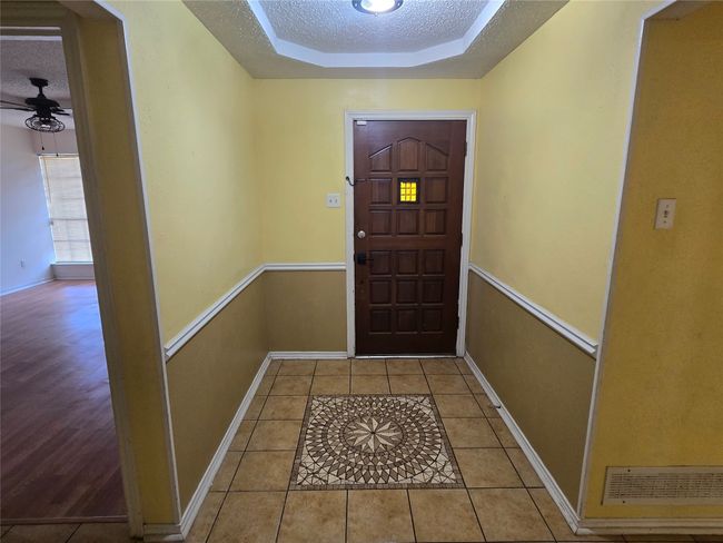 Entryway with a raised ceiling, a textured ceiling, ceiling fan, and tile patterned floors | Image 10