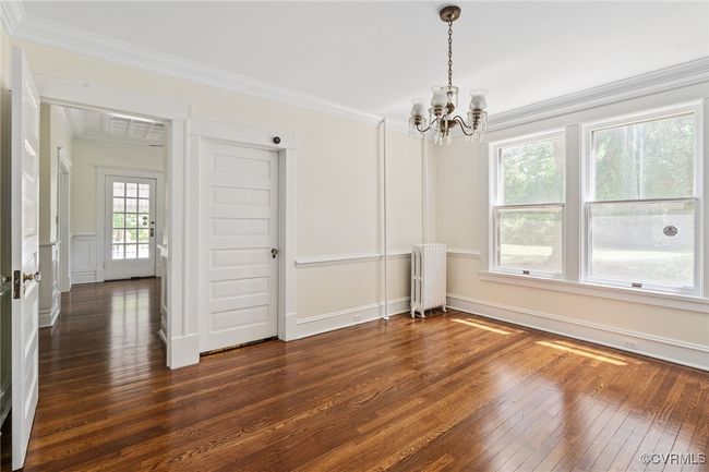 Dining room featuring radiator heating unit, a chandelier, dark wood flooring, ornamental molding, and baseboards | Image 16