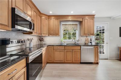 Kitchen with appliances with stainless steel finishes, light hardwood / wood-style floors, sink, and tasteful backsplash | Image 3