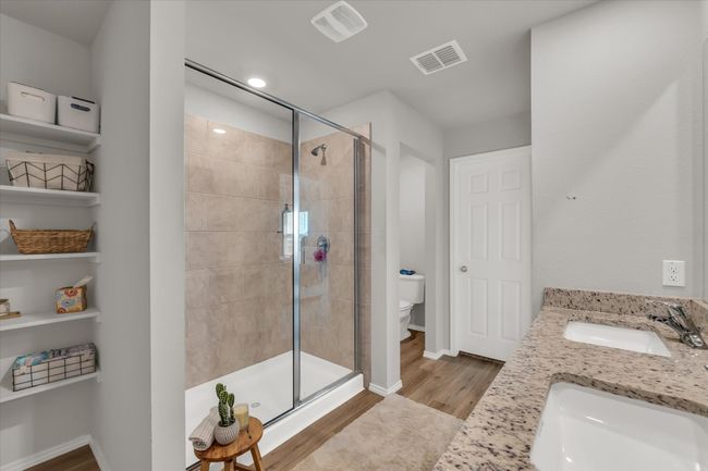 Full bath with a shower stall, toilet, wood finished floors, double vanity, and baseboards | Image 13
