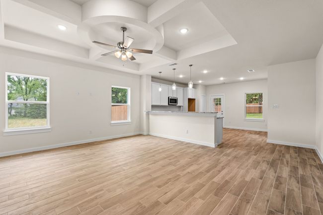 Unfurnished living room with coffered ceiling, a ceiling fan, recessed lighting, light wood-style floors, and baseboards | Image 11