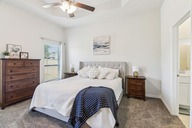 Bedroom featuring baseboards, a raised ceiling, a sink, ceiling fan, and light colored carpet | Image 15