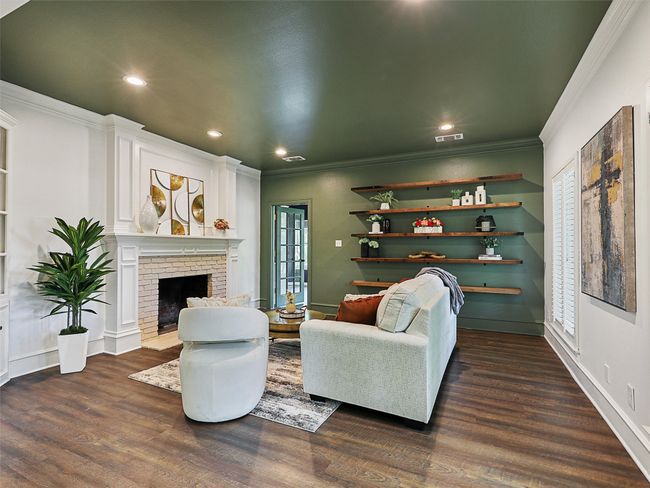 Living area featuring dark wood finished floors, visible vents, recessed lighting, a brick fireplace, and crown molding | Image 4