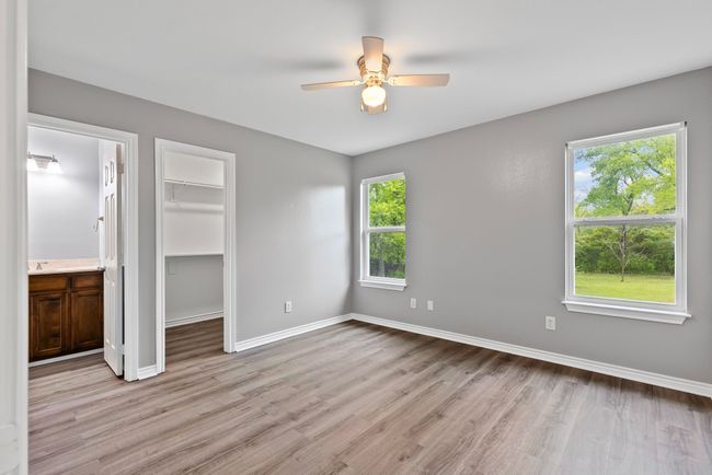 Primary bedroom featuring multiple windows, light wood-style floors, a spacious closet, and ensuite bathroom | Image 12