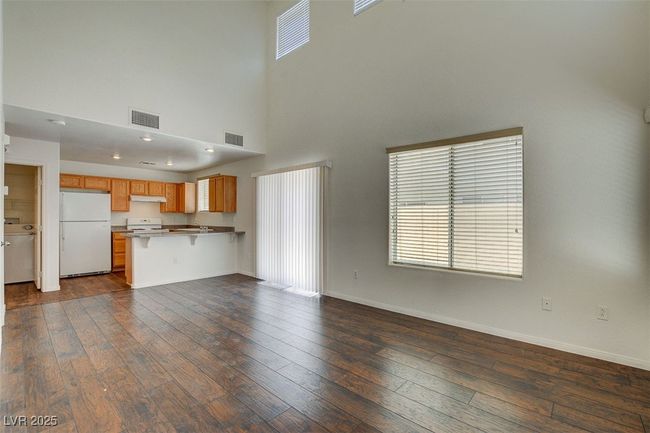 Unfurnished living room featuring a towering ceiling, visible vents, and dark wood-type flooring | Image 4