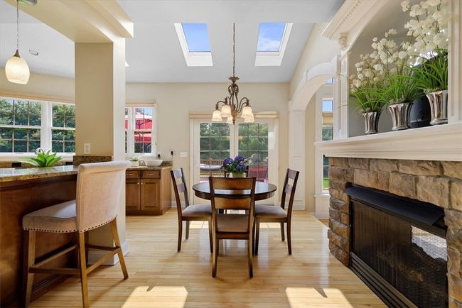 The skylights above allow natural light to brighten the breakfast area with the double-sided fireplace adding a warm ambience to this space. Extend activities to the outside through the door. | Image 17