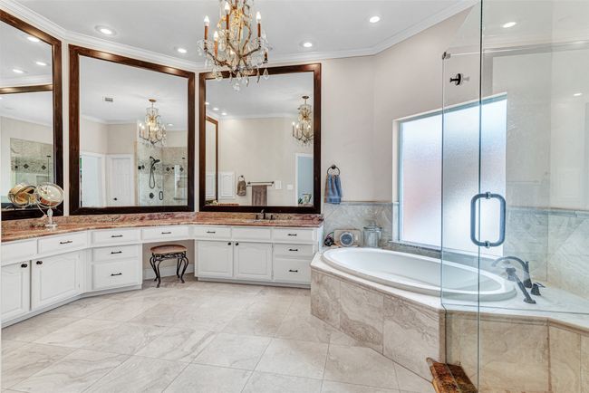 The spa-inspired primary bath has been updated with fresh paint, decorator chandelier and hardware. Not to mention and relaxing jetted tub under a frosted glass window and oversized vanity with abundant storage space. | Image 11